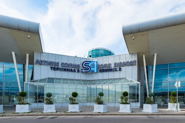 Modern glass and steel facade of Sofia Airport Terminal 2 with distinctive architectural design and blue-tinted windows under a cloudy sky.