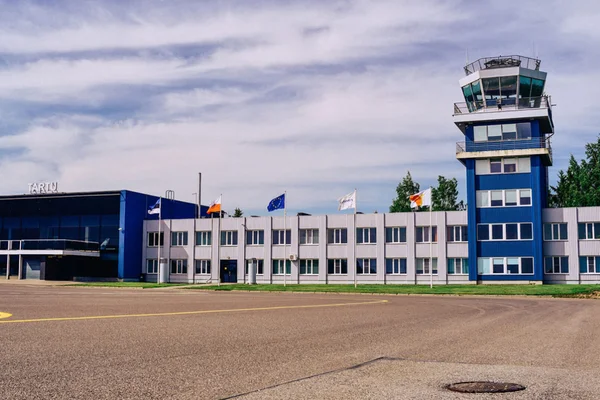 Terminal de l'aéroport de Tartu avec tour de contrôle bleue et drapeaux.