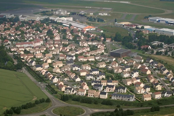 Vista aérea de área residencial suburbana cerca del Aeropuerto de Paris-Saclay-Versailles con campos verdes.