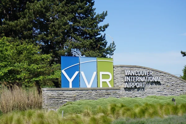 Panneau logo YVR à côté d'un mur en pierre pour l'aéroport international de Vancouver.