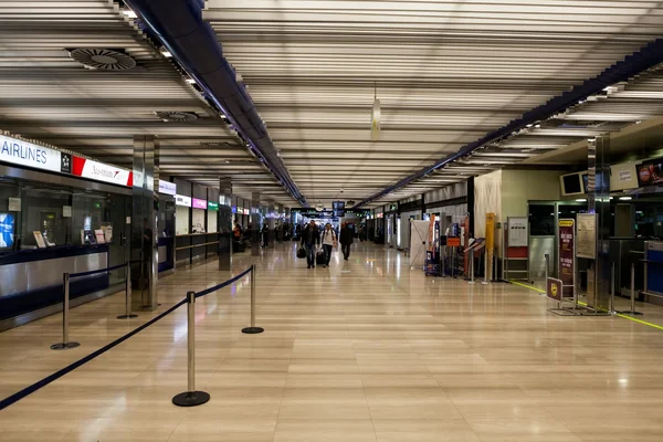 Zagreb Franjo Tuđman Airport departures hall with airline counters, queue barriers, and passengers in a modern terminal building.