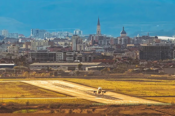 Des champs agricoles et un tracteur avec la skyline de Cluj-Napoca et ses églises en arrière-plan à l'aéroport Avram Iancu Cluj.