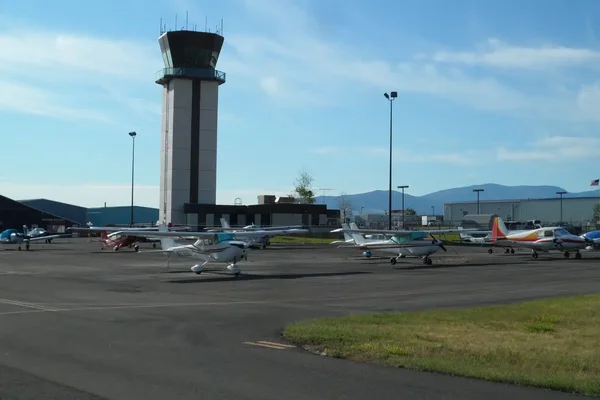 Terminal de l'aéroport régional de Helena avec toit vert, avion garé et montagnes sous un ciel bleu.
