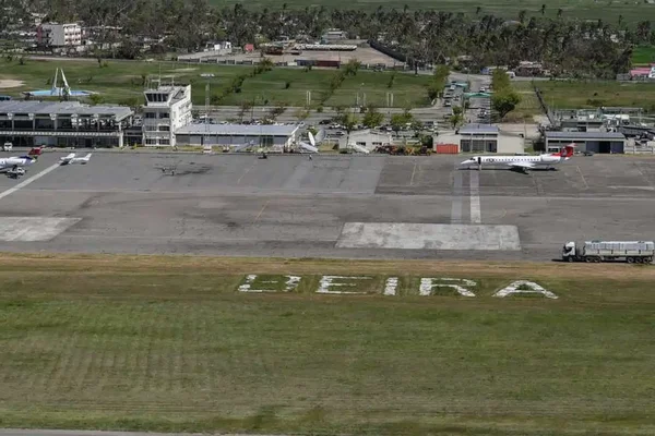 Vista aerea dell'aeroporto di Beira mostra pista, terminale e aereo parcheggiato circondato da campi.