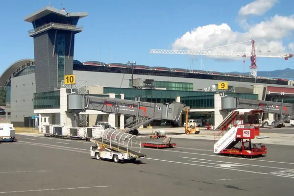 Terminal de l'aéroport international Juan Santamaría avec tour de contrôle et avions garés.