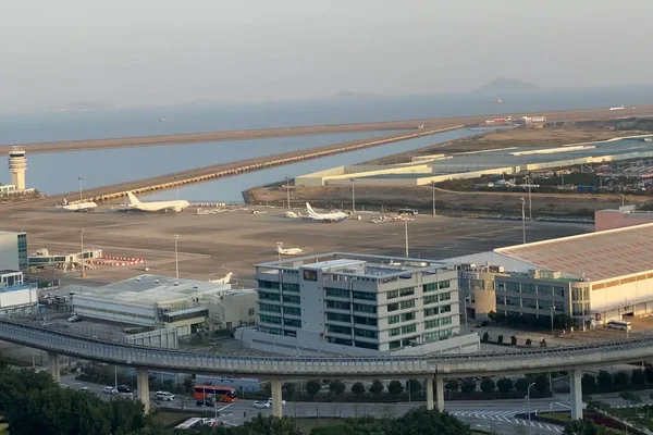 Вид аэропорта Макао со взлётной полосой, терминалами и береговой линией на закате.
