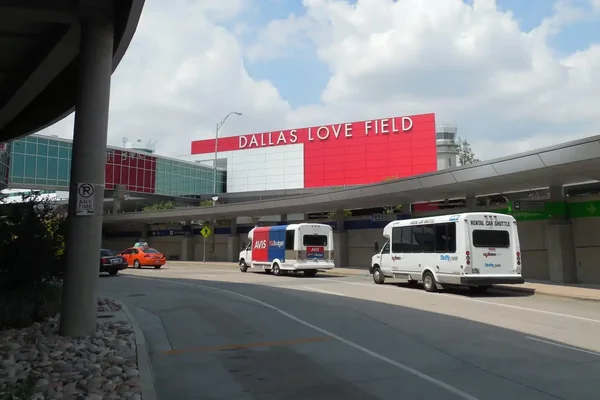 Vue extérieure du terminal de l'aéroport Dallas Love Field avec signalétique rouge.