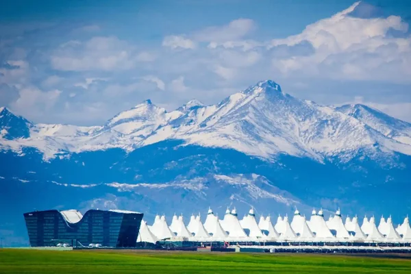 Terminal de l'aéroport international de Denver avec toit blanc caractéristique et Rocheuses.