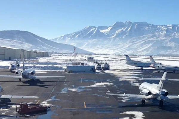 Vue aérienne de l'aéroport de Heber Valley avec montagnes enneigées et vallées vertes.