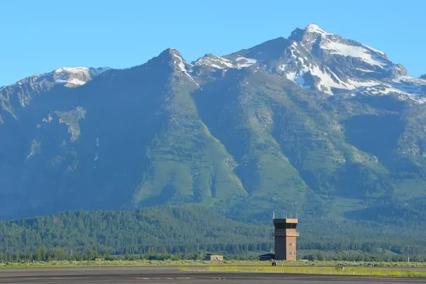 Terminal de l'aéroport de Jackson Hole avec poutres en bois et montagnes enneigées.