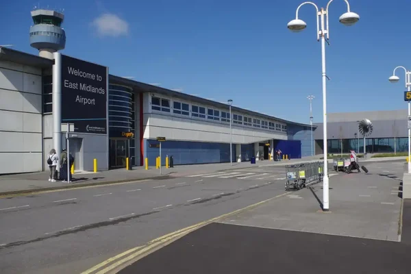 Entrada del Aeropuerto de East Midlands con letrero de bienvenida y torre de control.