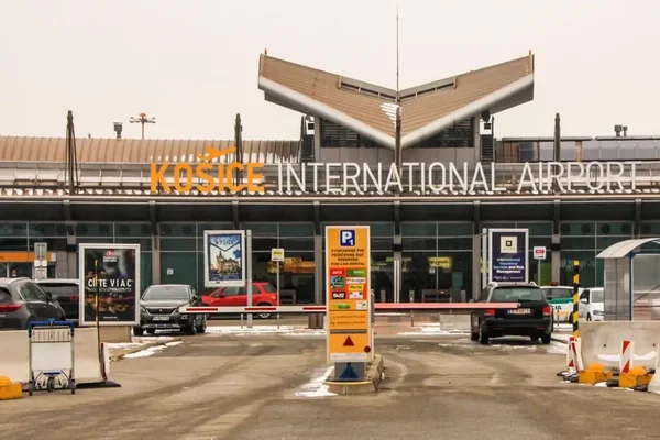 Terminal de l'aéroport Košice la nuit avec signalétique illuminée et pavé humide.