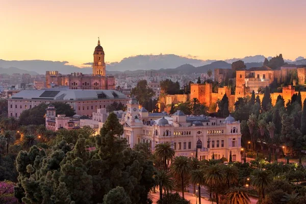 Twilight panoramic view of Málaga with the illuminated cathedral, Alcazaba fortress, and city lights
