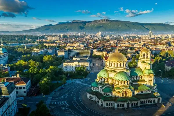 Aerial view of Sofia, Bulgaria featuring the golden-domed Alexander Nevsky Cathedral with mountain backdrop and cityscape