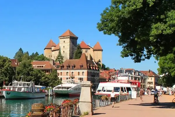 Canal del lago de Annecy con árboles y barcos y la iglesia Notre-Dame-de-Liesse