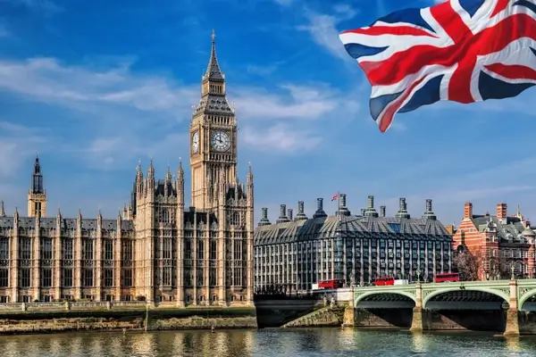 La bandera del Reino Unido ondeando en lo alto del Big Ben y las Casas del Parlamento en Londres, con autobuses rojos de dos pisos en el Puente de Westminster