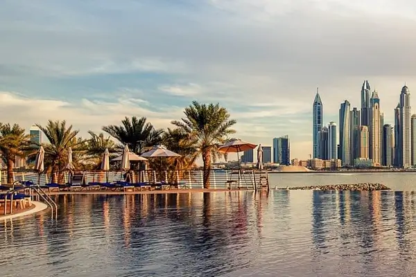 Blick von einem Swimmingpool auf die Küste des Persischen Golfs in Dubai mit Yachten und Wolkenkratzern