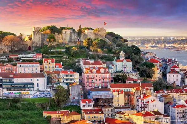 Lisbon cityscape at sunset with historic São Jorge Castle overlooking colorful buildings and the Tagus River