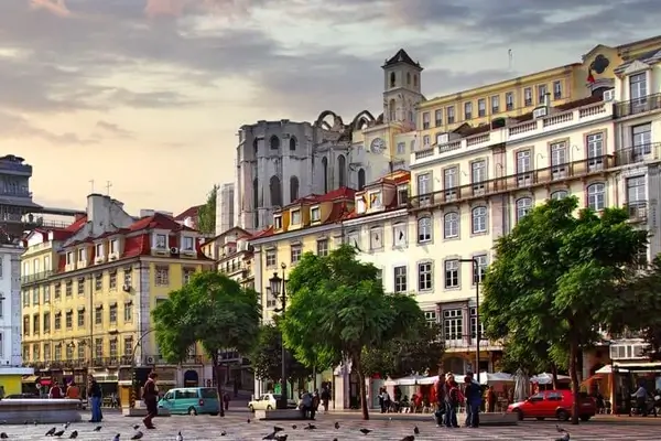 Skyview of Rossio square in Lisbon in the sunset with trees and people walking by