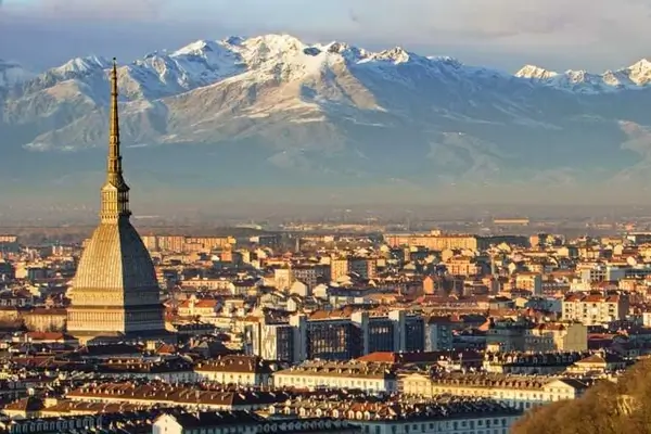 Aerial view of the rooftops of Turin, Italy, at sunset with snow-capped mountains in the background