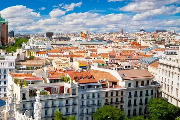 Luftaufnahme der historischen Stadtlandschaft von Madrid mit charakteristischen Terrakottadächern, klassischer Architektur und blauem Himmel mit Wolken
