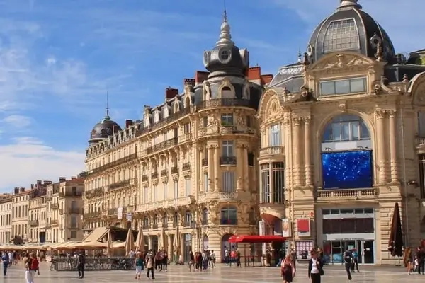 Gente paseando por la Place de la Comédie en Montpellier en un día soleado.