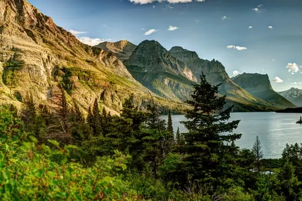 Lac alpin pittoresque entouré de pics montagneux dramatiques et de forêts de conifères dans le Glacier National Park, Montana