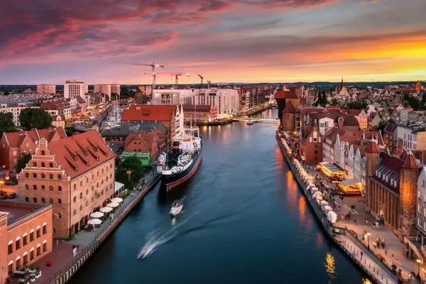 Vue du coucher de soleil sur le front de mer de Gdansk avec des bâtiments aux toits rouges, la rivière Motlawa et l'architecture historique en Pologne