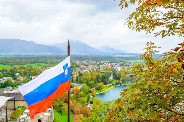 Russian flag overlooking Slovenian Alpine valley with river and green landscape nestled between mountains