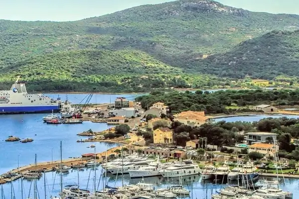 Horizonte de Porto Vecchio en Córcega con un ferry y yates y montañas de fondo