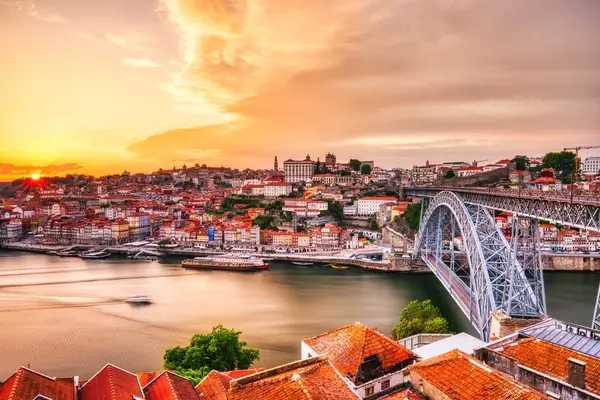 Sunset over Porto with Dom Luis Bridge spanning the Douro River, historic cityscape with terracotta roofs