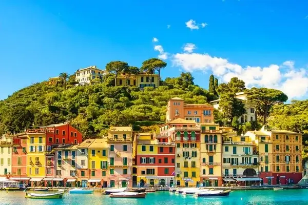 Daylight picture of Portofino in Italy with colored houses and boats with a blue cloudy sky