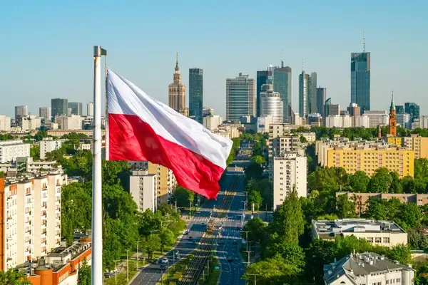 Drapeau polonais flottant au-dessus de la skyline de Warsaw avec des gratte-ciel modernes et des rues bordées d'arbres visibles