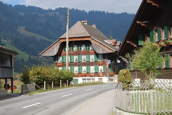Chalet suizo tradicional con persianas verdes anidado en los Alpes de Appenzell, mostrando la arquitectura alpina clásica y el paisaje montañoso.