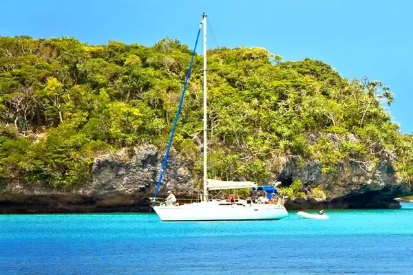 Vista di una barca in nuova caledonia con palme sullo sfondo