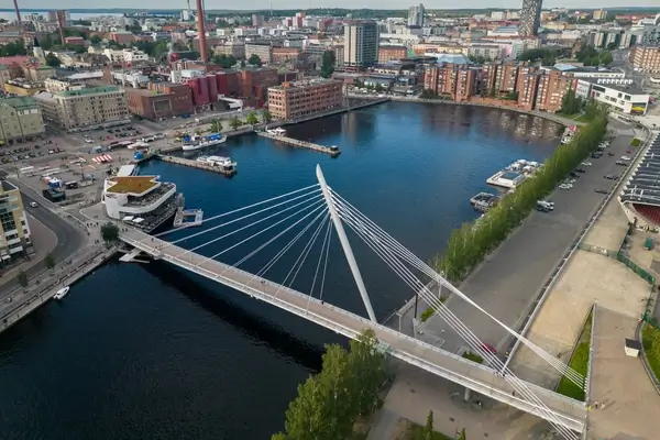 Une vue aérienne pittoresque de Tampere, en Finlande, mettant en avant l'infrastructure moderne de la ville, ses ponts et ses voies navigables sereines sous un ciel partiellement nuageux.