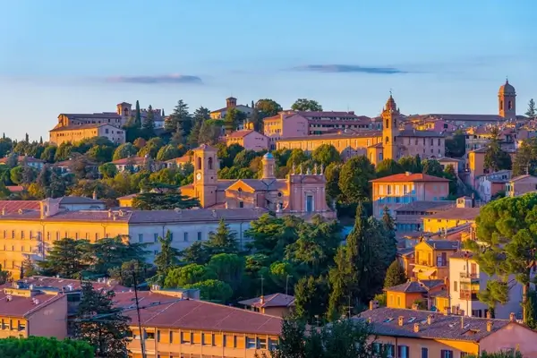 Golden sunset light illuminates the historic terracotta-roofed buildings and rolling hills of Perugia, Italy's charming medieval hilltop town.