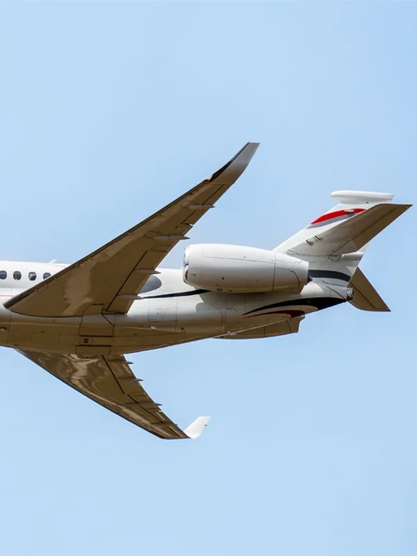 Ein Dassault Falcon Privatjet kreuzt im hellblauen Himmel, von unten gesehen