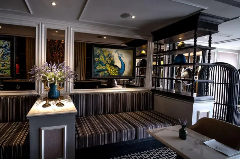 A luxury hotel dining lounge with peacock artwork and striped seating, Dubai