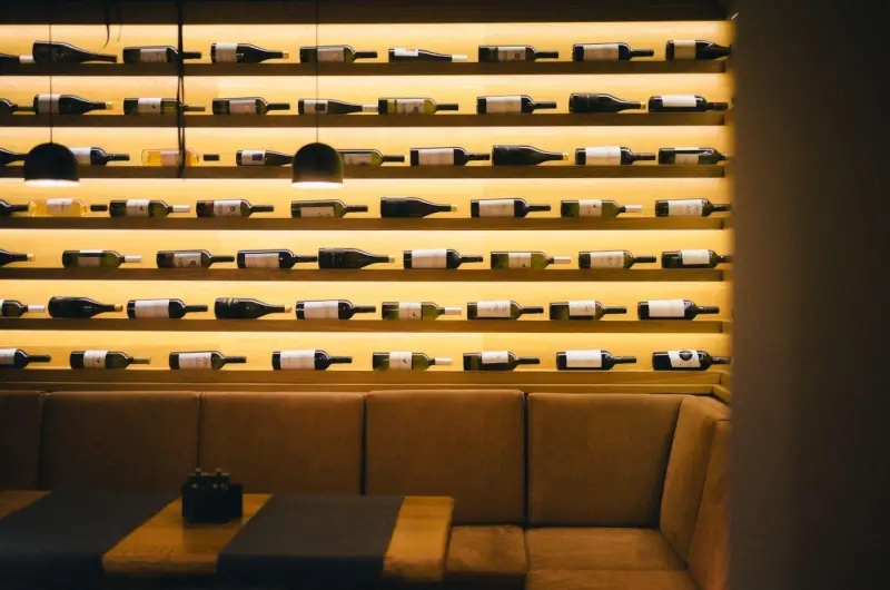Una parete di vini illuminata dietro una zona salotto, a Berlino