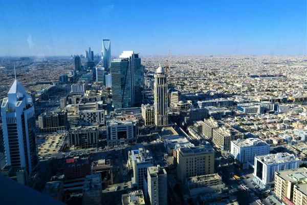 Panorama Rijadu za dnia, z wieżowcem Kingdom Centre górującym nad miastem pod czystym błękitnym niebem.
