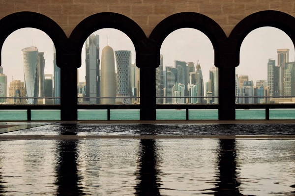 Lo skyline di West Bay a Doha visto attraverso archi in pietra, con i riflessi in una vasca in primo piano