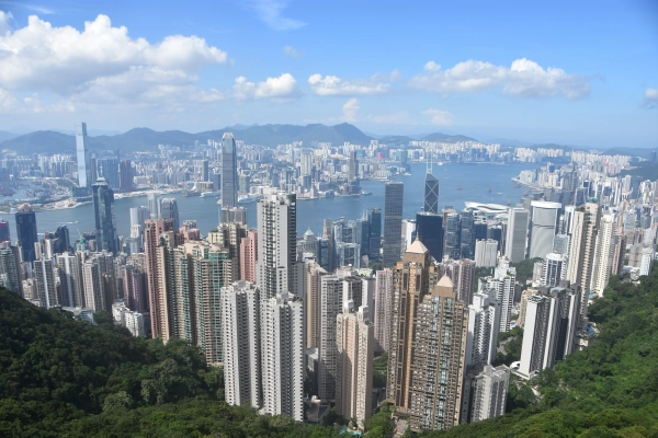 La skyline de Hong Kong et le port de Victoria vus depuis le pic Victoria, avec des pentes boisées au premier plan.