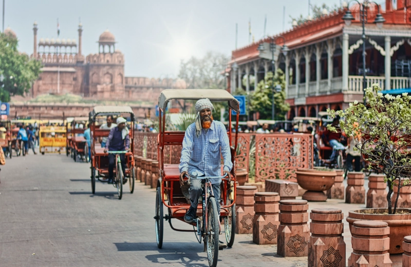 Cycle rickshaws on a street in Old Delhi, with the Red Fort in the background