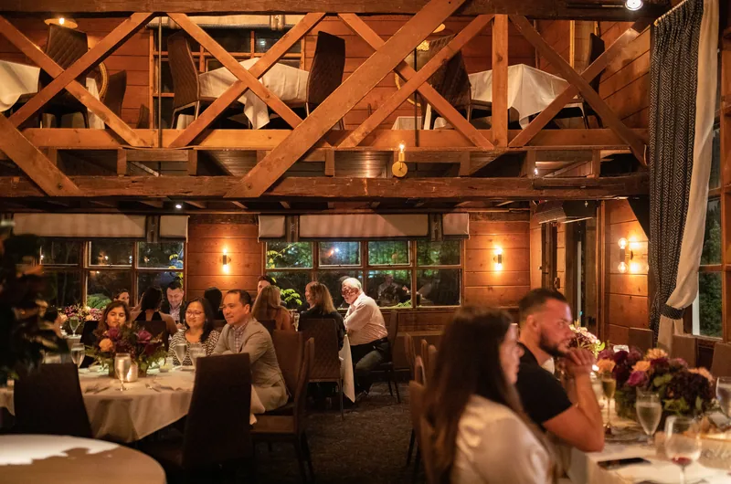 Sala restauracyjna z drewnianą konstrukcją i goście przy stołach w Saddle River Inn, New Jersey