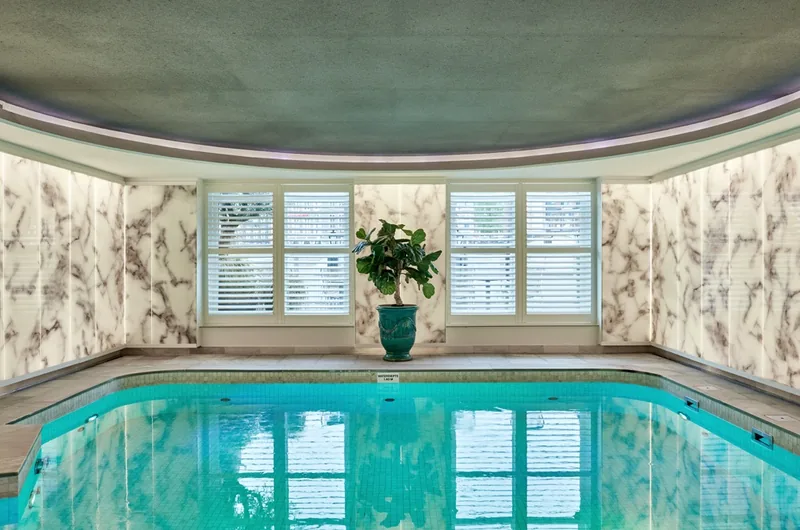 Piscina coperta con pareti effetto marmo e finestre con persiane al De L'Europe Amsterdam
