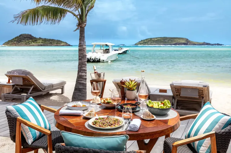 Стол для обеда на песке в ресторане Amis St. Barth отеля Le Barthélemy у залива