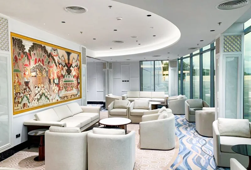Passenger lounge at Siam Land Private Jet Terminal in Phuket, with curved windows, pale seating and Thai artwork