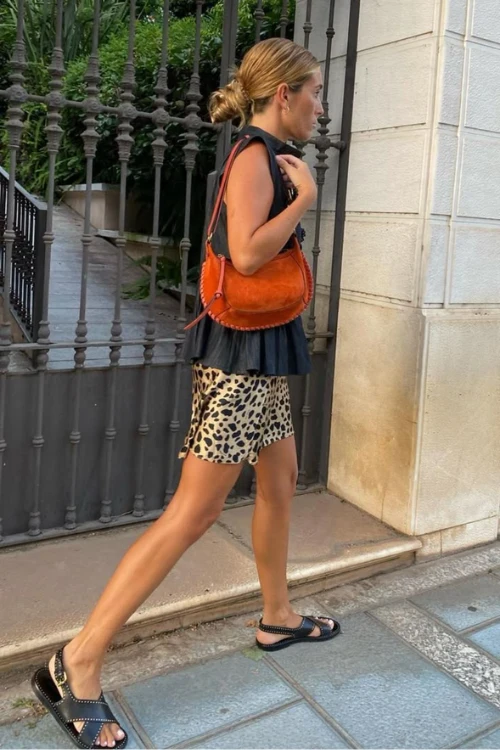 Leopard mini skirt styled with a black top and oversized orange bag. Punchy details and confident styling.