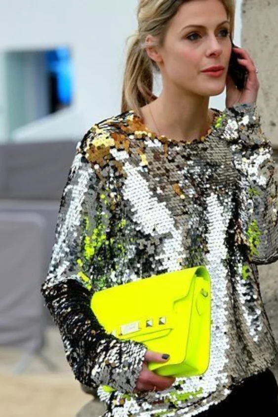 Statement sequin top with neon clutch. Bold shimmer layered for an offbeat modern party look.